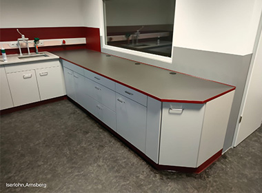 Laborarbeitsbereich in L-Form mit Farbakzenten in Rot